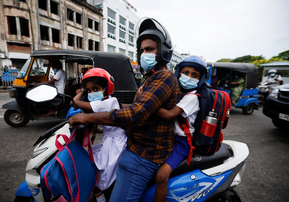 A man drives his scooter as he passes by a protest demanding justice for K.D. Chaminda Lakshan, 41, who died after getting caught up in a clash as he went to the petrol station at Rambukkana to fill his motorcycle on Tuesday amid the country's ongoing economic crisis, in Colombo, Sri Lanka, April 22, 2022. REUTERS/Navesh Chitrakar