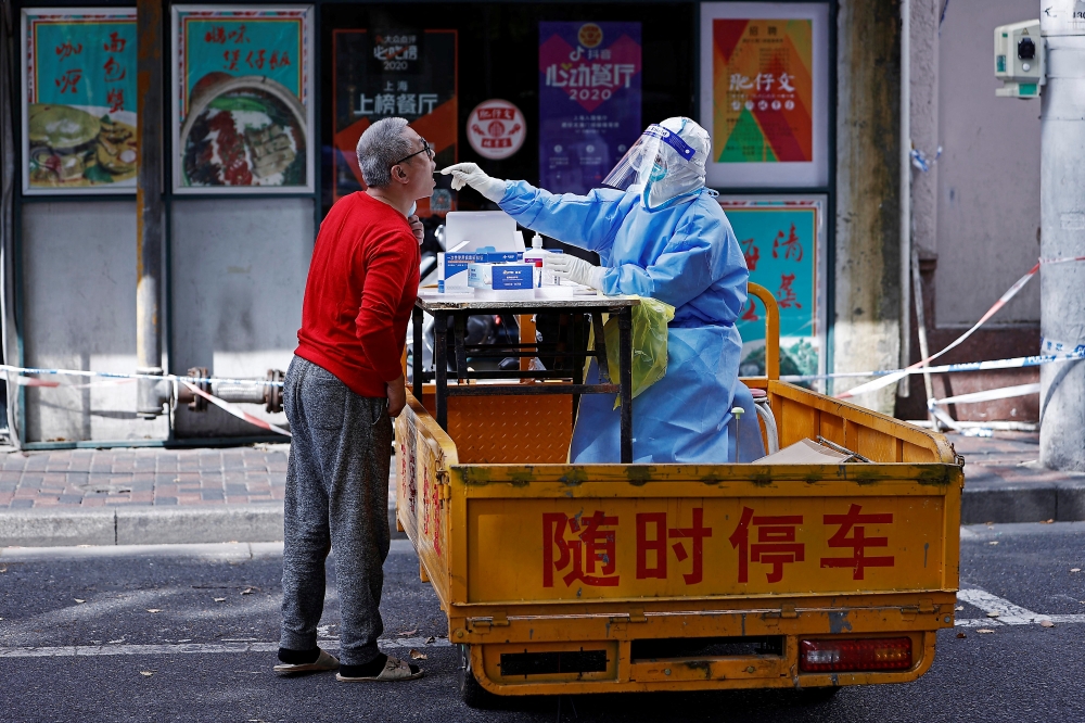 A medical worker in a protective suit collects a swab from a resident for nucleic acid testing, amid the coronavirus disease (COVID-19) outbreak in Shanghai, China April 22, 2022. cnsphoto via REUTERS