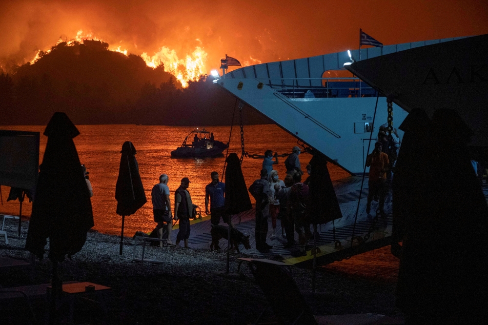 People board a ferry during evacuation as a wildfire burns in the village of Limni, on the island of Evia, Greece, August 6, 2021. REUTERS/Nicolas Economou/File Photo
 