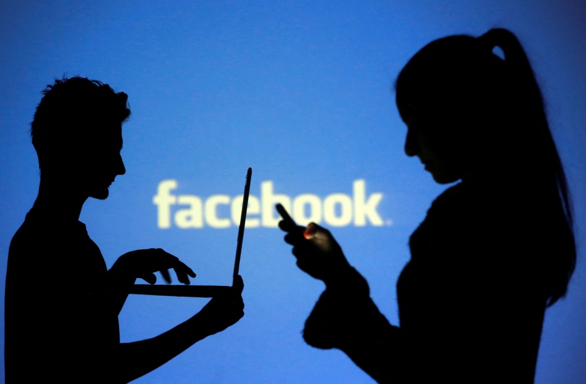 FILE PHOTO: People are silhouetted as they pose with laptops in front of a screen projected with a Facebook logo, in this picture illustration taken in Zenica October 29, 2014. REUTERS/Dado Ruvic/File Photo
