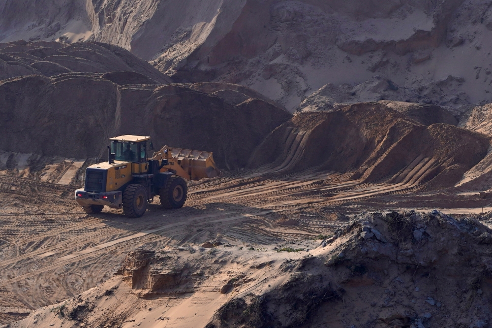 A worker operates a front loader in an area cleared for sand mining on a dried lake bed of Poyang Lake in Jiujiang, Jiangxi province, China December 11, 2019. REUTERS/Aly Song/File Photo