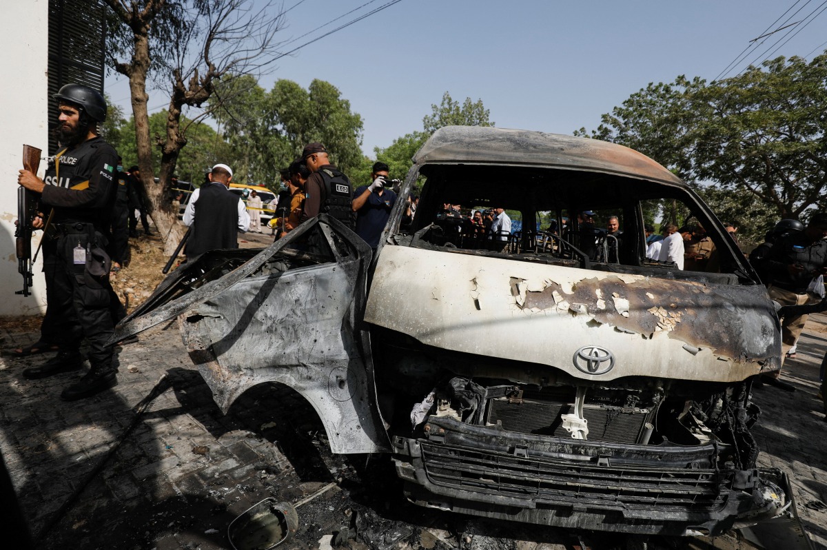 Police officers and members of the investigation team gather near a passenger van, after a blast at the entrance of the Confucius Institute University of Karachi, Pakistan April 26, 2022. REUTERS/Akhtar Soomro
