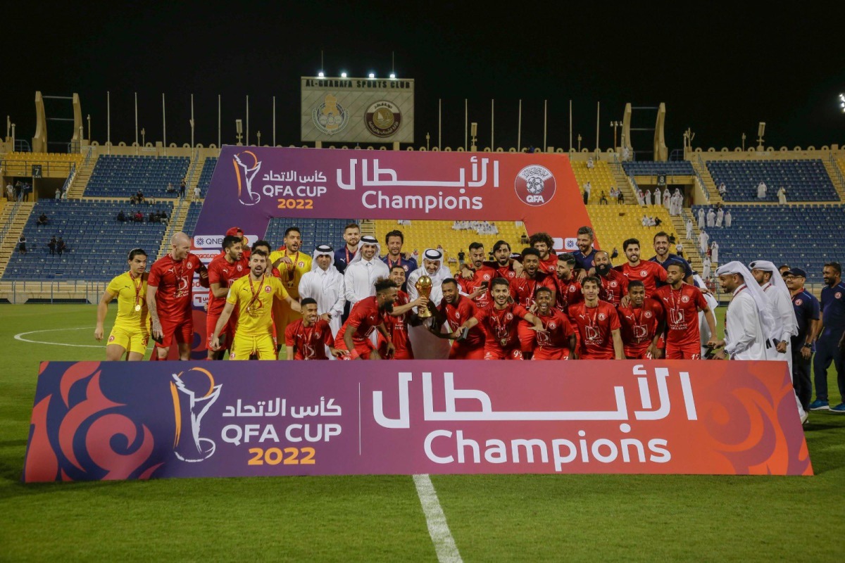 Al Arabi players and officials celebrate with the trophy after winning the QFA Cup at the Thani bin Jassim Stadium, yesterday.