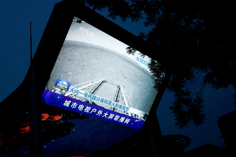 A screen broadcasts a CCTV state media news bulletin, showing an image of Mars taken by Chinese Mars rover Zhurong as part of the Tianwen-1 mission, in Beijing, China, May 19, 2021. REUTERS/Thomas Peter/File Photo/File Photo