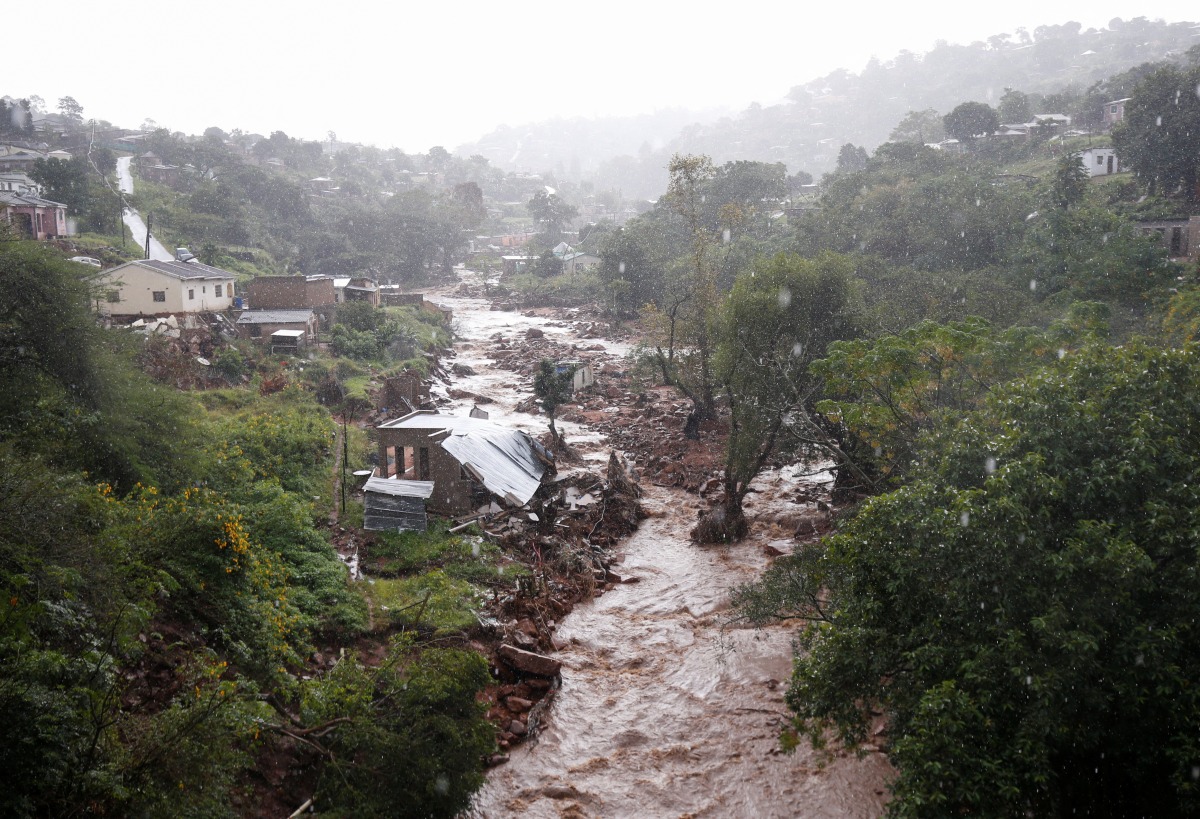 A river runs high after heavy rains, next to homes which were damaged during previous flooding, in kwaNdengezi near Durban, South Africa, May 22, 2022. REUTERS/Rogan Ward
