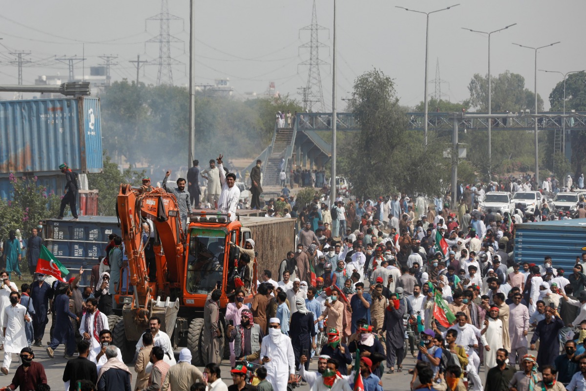 Supporters of the Pakistan Tehreek-e-Insaf (PTI) political party sit atop of a crane after they removed the shipping containers, used to block the roads to prevent them from attending the protest march planned by ousted Prime Minister Imran Khan in Islamabad, in Rawalpindi, Pakistan May 25, 2022. REUTERS/Akhtar Soomro
