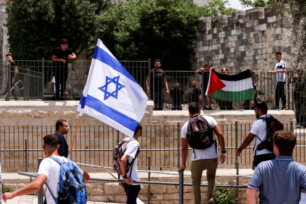 Israelis stand with an Israeli flag opposite to Palestinians with Palestinian flag next to Damascus gate to Jerusalem's Old City May 29, 2022. REUTERS/Ammar Awad