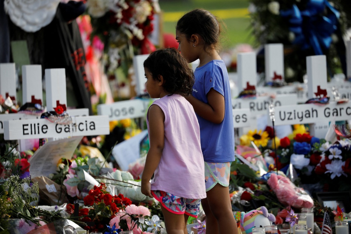 Children pay their respects in front of the memorial at Robb Elementary school, where a gunman killed 19 children and two adults, in Uvalde, Texas, U.S. May 28, 2022. REUTERS/Marco Bello
