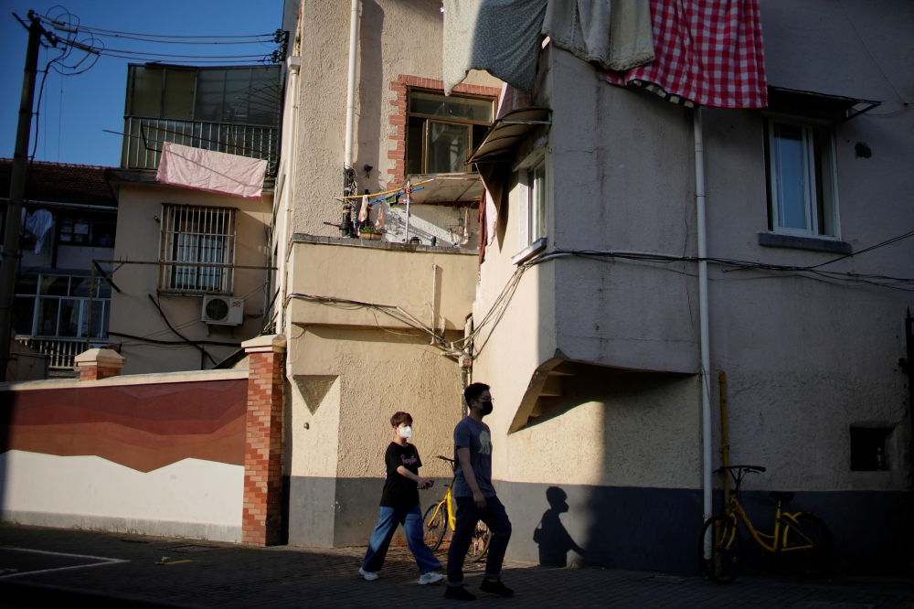 People wearing face masks walk past a residential building, after the lockdown placed to curb the coronavirus disease (COVID-19) outbreak was lifted in Shanghai, China June 2, 2022. Reuters/Aly Song