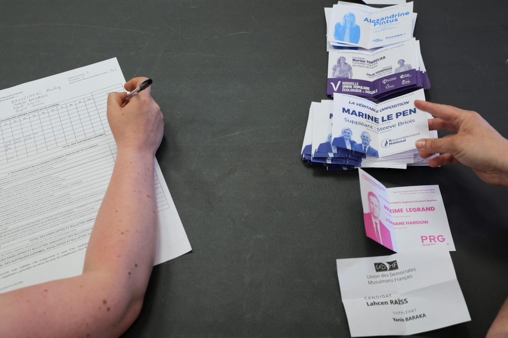 An official counts ballots for the first round of French parliamentary elections, at a polling station in Henin-Beaumont, France, June 12, 2022. Reuters/Pascal Rossignol