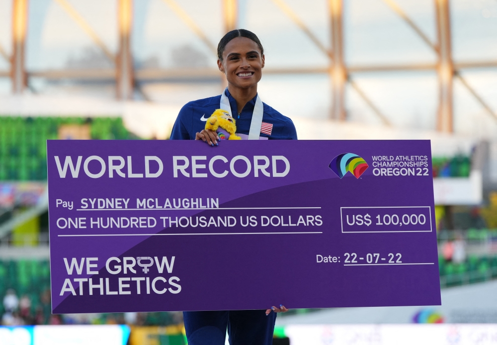 Gold medallist Sydney McLaughlin of the U.S. celebrates on the podium with a cheque during the medal ceremony after winning the women's 400 metres hurdles final and setting a new world record REUTERS/Aleksandra Szmigiel