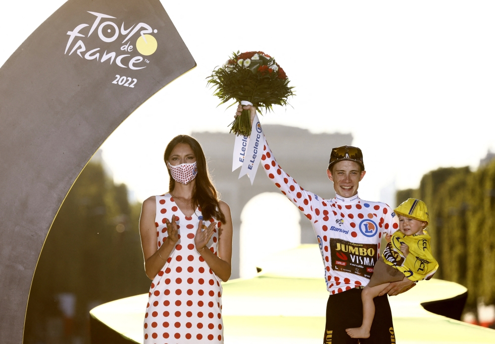 Visma's Jonas Vingegaard celebrates on the podium holding his daughter Frida after winning the Tour de France on July 24, 2022. (REUTERS/Christian Hartmann)