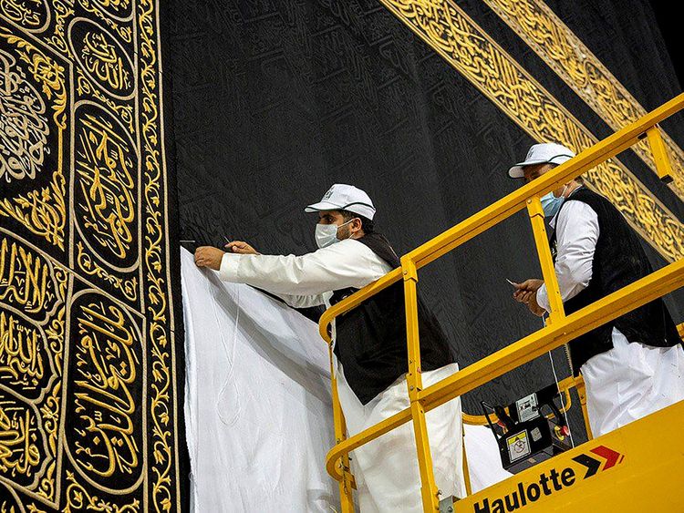 Workers wearing protective face masks work on raising the Kiswa, a silk cloth covering the Holy Kaaba, before the annual pilgrimage season, at the Grand Mosque in Mecca, Saudi Arabia July 22, 2020.