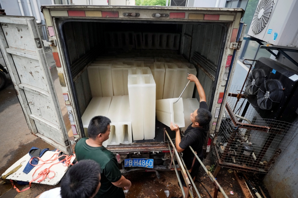 Employees move ice blocks onto a truck to send them to a testing site for the coronavirus disease (COVID-19), at Shanghai Yuhu ice-making factory, amid a heatwave warning in Shanghai, China July 26, 2022. REUTERS/Aly Song