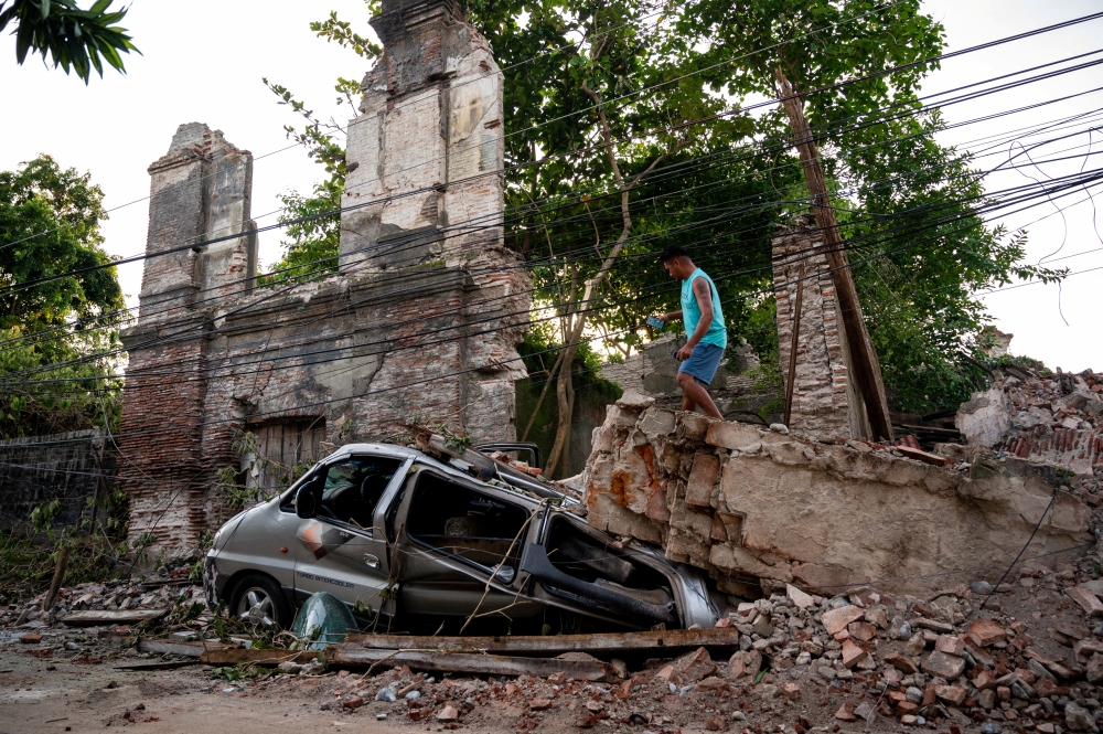 A man inspects a damaged car in the aftermath of an earthquake in Vigan City, Ilocos Sur, Philippines, July 28, 2022. REUTERS/Lisa Marie David