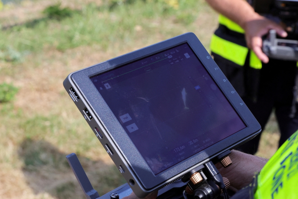 A firefighter looks at the screen as drone flying above Seine river monitors whale's movements at Saint-Pierre-la-Garenne, France, August 4, 2022. (Reuters/Pascal Rossignol/File Photo)