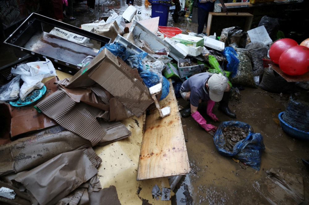 An employee of a herbal medicine shop cleans up debris at a traditional market damaged by flood after torrential rain, in Seoul, South Korea, August 9, 2022. REUTERS/Kim Hong-Ji/File Photo