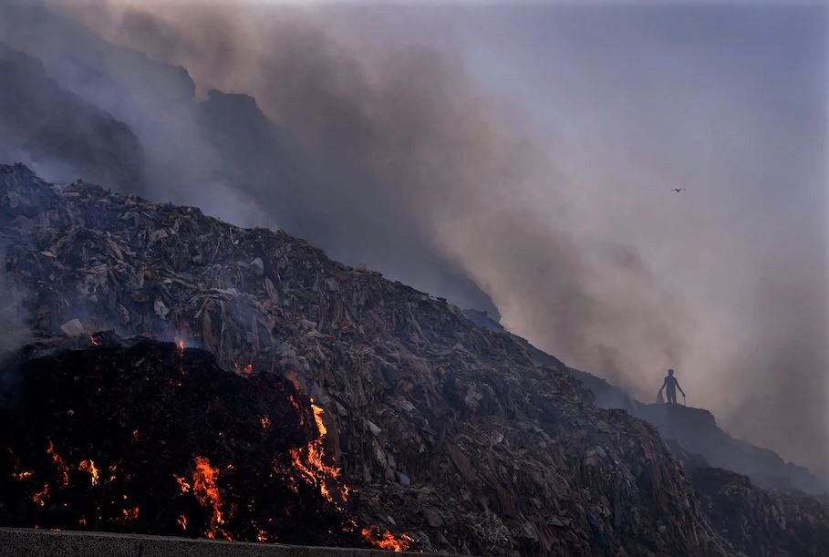 A person picks through trash for reusable items as a fire rages at the Bhalswa landfill in New Delhi on April 27, 2022. (Image credit: Manish Swarup via AP)