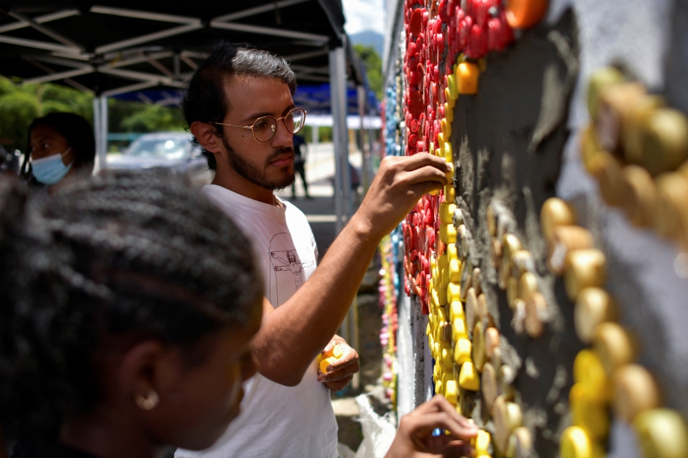 Venezuelan artist Oscar Olivares uses bottle caps to create colorful eco-mural to raise awareness for recycling, in Caracas, Venezuela August 19, 2022. Reuters/Gaby Oraa