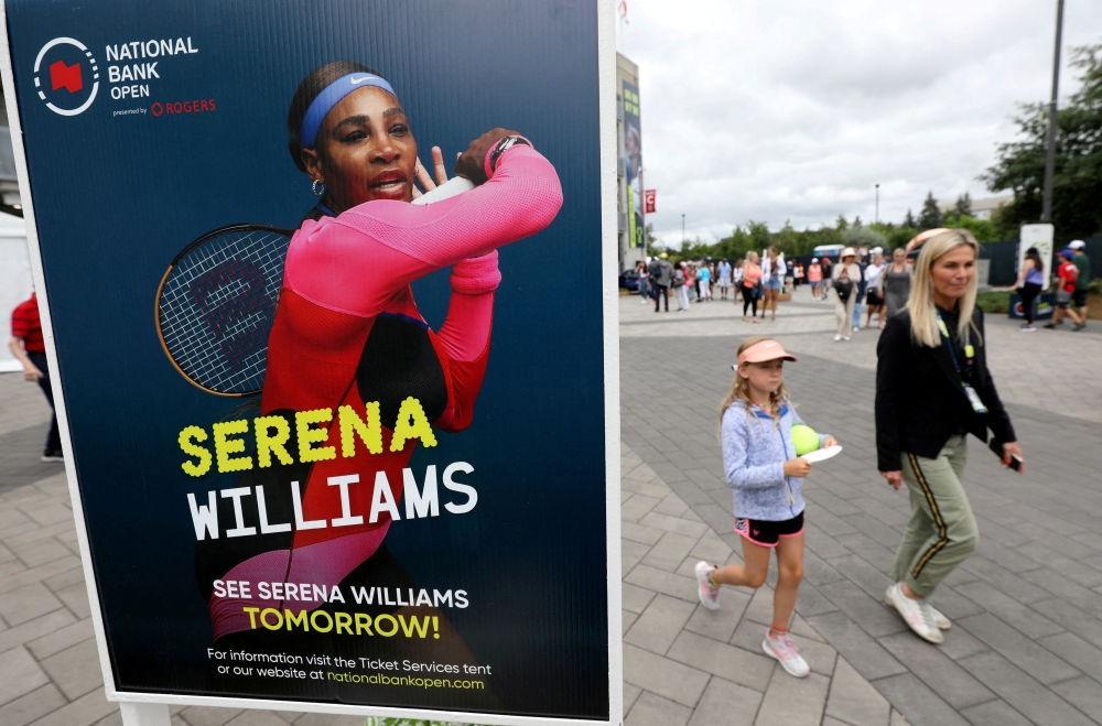 People pass a poster advertising the match of veteran tennis player Serena Williams, who said that she plans to retire after the 2022 US Open, outside a stadium at the National Bank Open in Toronto, Ontario, Canada, August 9, 2022. (REUTERS/Chris Helgren)