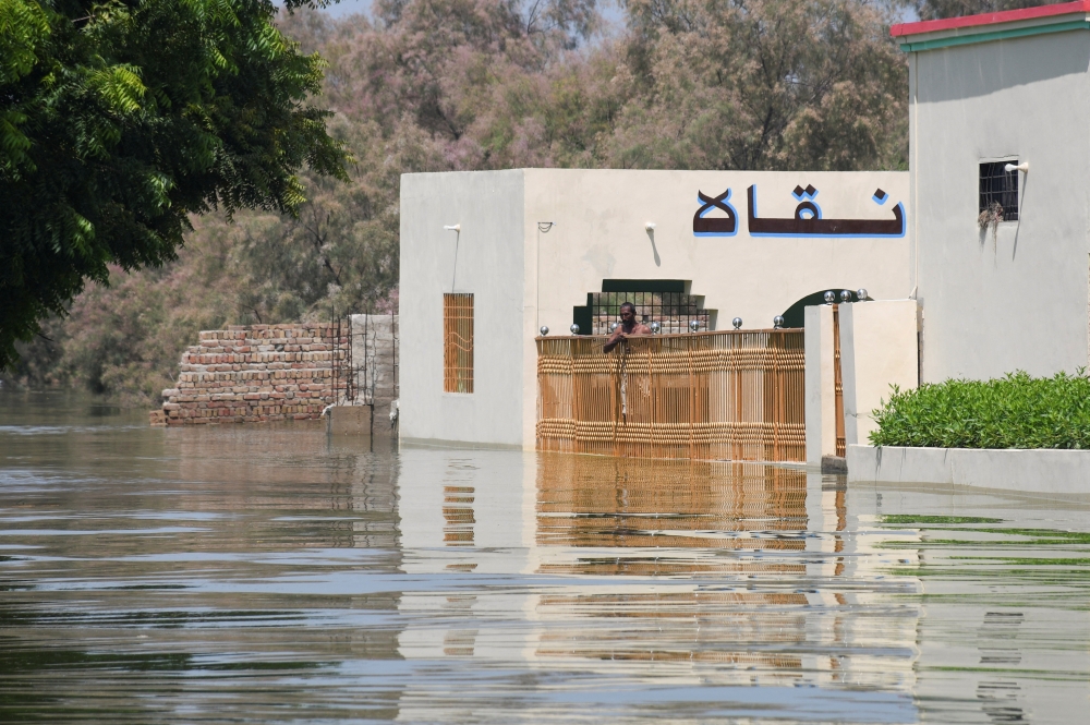 A man stands at the main entrance of a building amid floodwater in village Arazi, in Sehwan, Pakistan September 11, 2022. Reuters/Yasir Rajput 