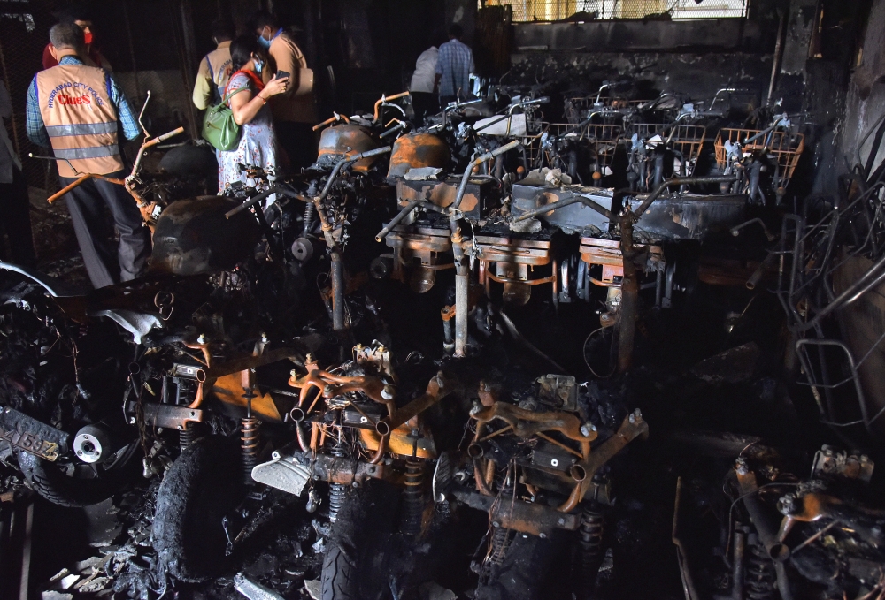 Police officials stand amidst damaged scooters after a fire broke out at an electric scooter showroom in the southern city of Secunderabad, India, September 13, 2022. REUTERS/Stringer