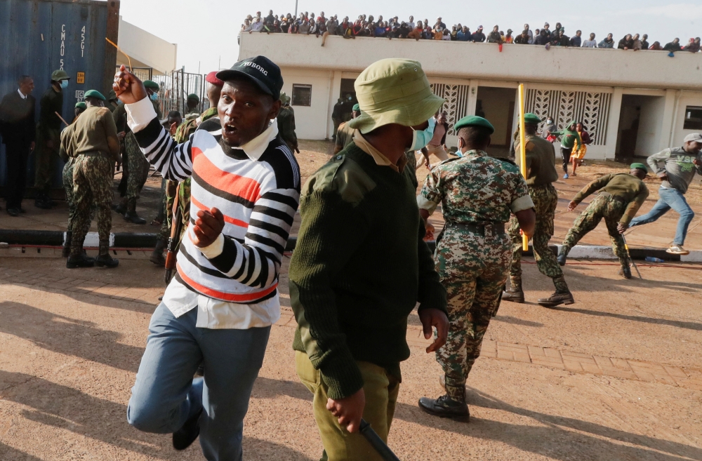 A man runs past riot police as they attempt to control people jostling to attend the inauguration of Kenya's President William Ruto before his swearing-in ceremony at the Moi International Stadium Kasarani, in Nairobi 