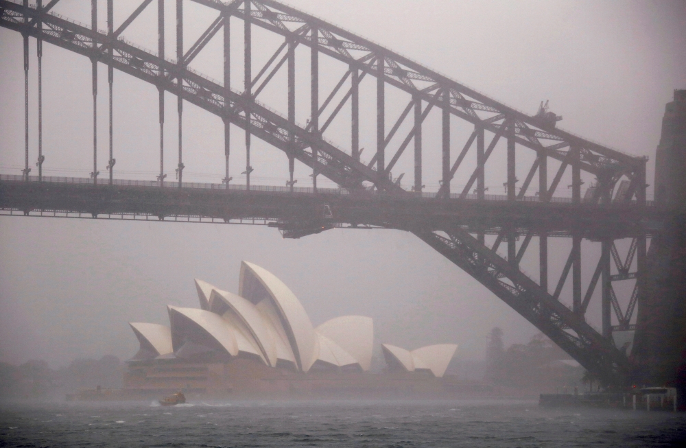 A boat passes under the Sydney Harbour Bridge and in front of the Sydney Opera House as strong winds and heavy rain hit the city of Sydney, Australia, November 28, 2018. REUTERS/David Gray