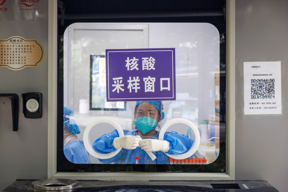 A pandemic prevention worker sits in a nucleic acid testing booth following a coronavirus disease (Covid-19) outbreak in Beijing, China, September 13, 2022. (REUTERS/Thomas Peter)