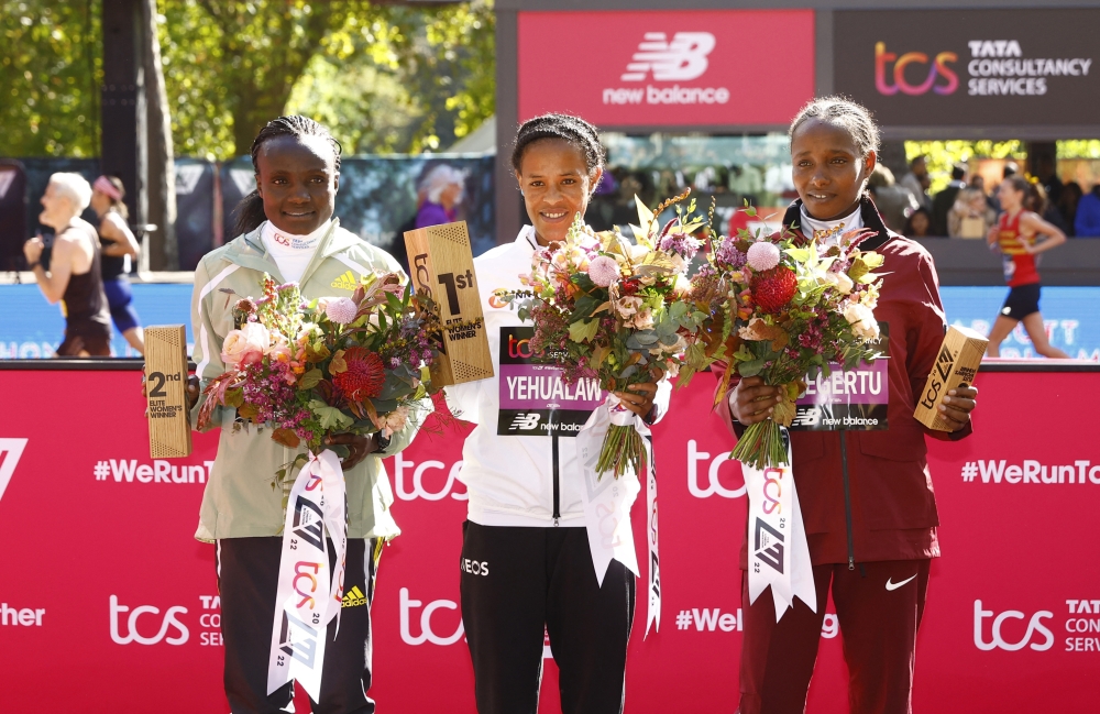 Ethiopia's Yalemzerf Yehualaw celebrates on the podium after winning the women's elite race of the London Marathon alongside second place Kenya's Joyciline Jepkosgei and third place Ethiopia's Alemu Megertu in London on October 2, 2022.   Action Images via Reuters/Andrew Boyers