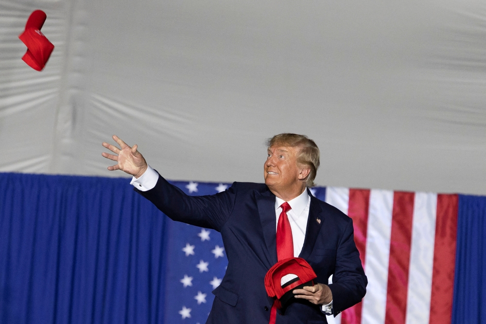 Former US president Donald Trump tosses caps to the crowd during a rally ahead of the midterm elections, in Minden, Nevada, US, on October 8, 2022. REUTERS/Carlos Barria