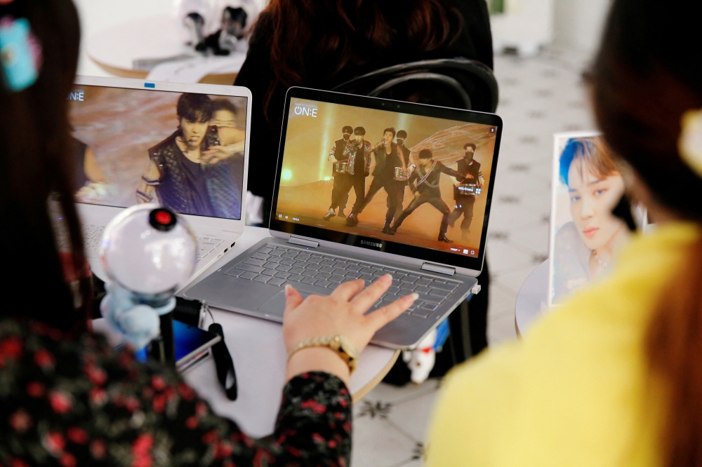 Fans of K-pop idol boy band BTS watch a live streaming online concert at a cafe in Seoul, South Korea October 10, 2020. Reuters/Heo Ran/File Photo