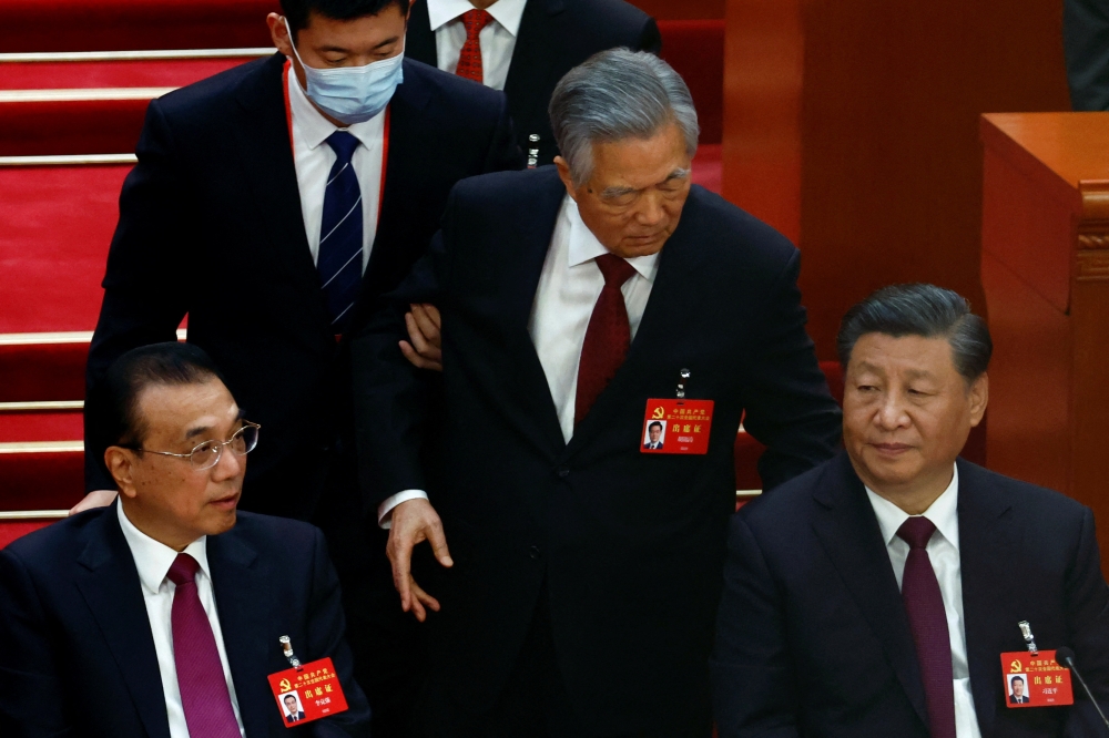 Former Chinese president Hu Jintao leaves his seat next to Chinese President Xi Jinping and Premier Li Keqiang at the Great Hall of the People in Beijing, China October 22, 2022. Reuters/Tingshu Wang