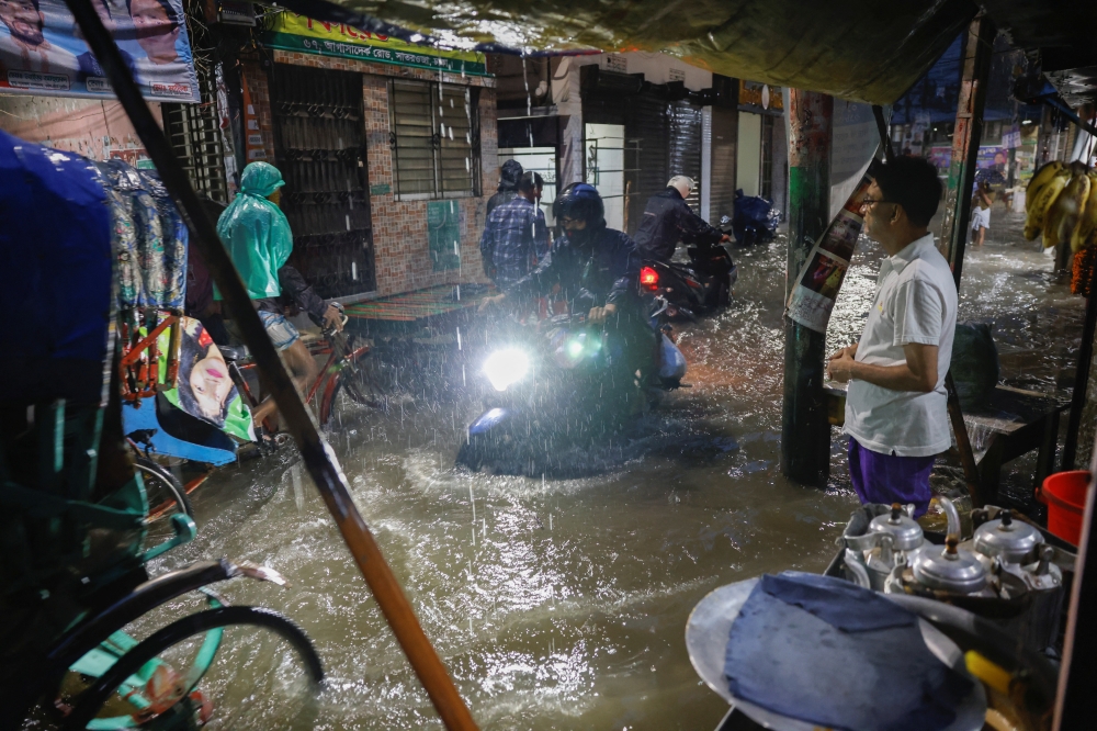 People ride rickshaws and motorcycles on a flooded street, amid continuous rain before Cyclone Sitrang hits the country in Dhaka, Bangladesh, October 24, 2022. (REUTERS/Mohammad Ponir Hossain)