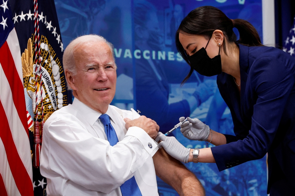 US President Joe Biden receives an updated coronavirus disease (COVID-19) vaccine while launching a new plan for Americans to receive booster shots and vaccinations, onstage in an auditorium on the White House campus in Washington, US, October 25, 2022. (REUTERS/Jonathan Ernst)