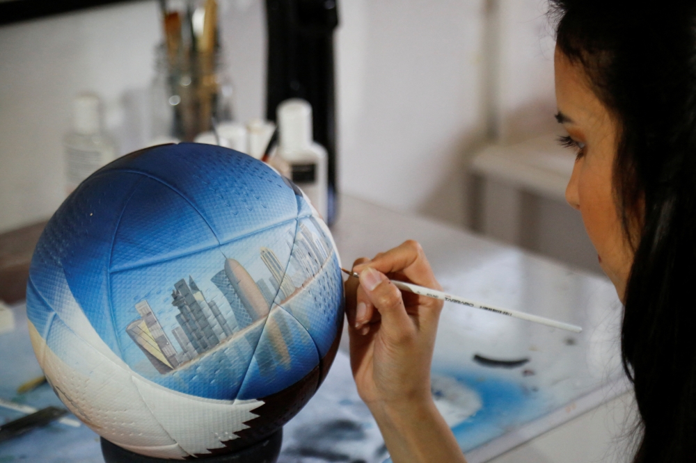 Paraguayan artist Lili Cantero, 29, paints a soccer ball with the skyline of Doha, Qatar, ahead of the 2022 FIFA World Cup, in San Lorenzo, Paraguay October 15, 2022. REUTERS/Cesar Olmedo