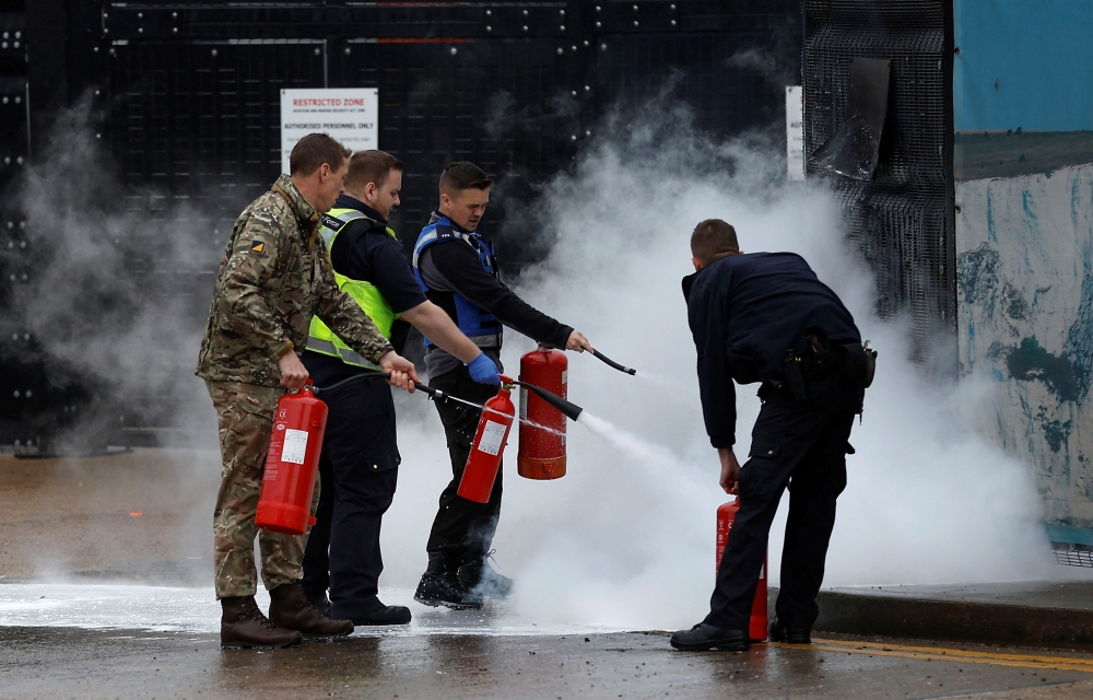 Members of the military and UK Border Force extinguish a fire from a petrol bomb, targeting the Border Force centre in Dover, Britain, October 30, 2022. (REUTERS/Peter Nicholls)