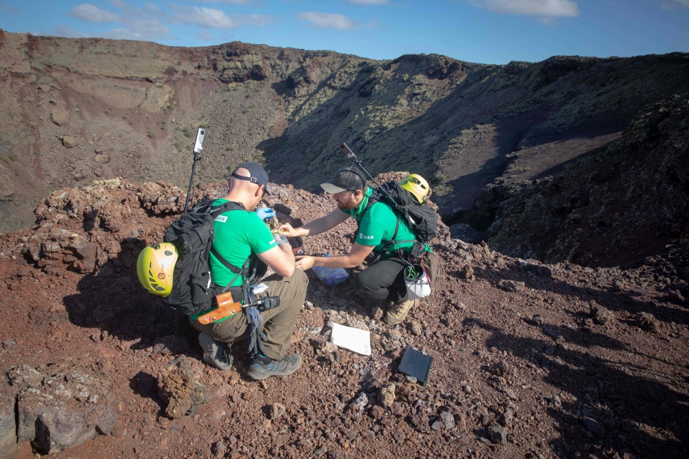 German astronaut Alexander Gerst (L) collects sample of an ancient volcano during a training program in Lanzarote to learn how to explore the Moon and Mars in the Timanfaya National Park on November 10, 2022. (Photo by DESIREE MARTIN / AFP)