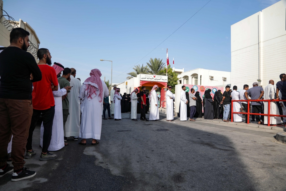 Bahrainis queue in front of a polling station on the island of Muharraq, north of the capital Manama, during parliamentary elections, on November 12, 2022. (AFP)