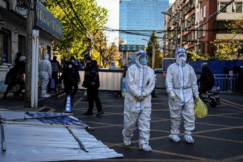 Health workers are seen near a residential area under lockdown due to Covid-19 coronavirus restrictions in Beijing on November 13, 2022. (Photo by Noel CELIS / AFP)