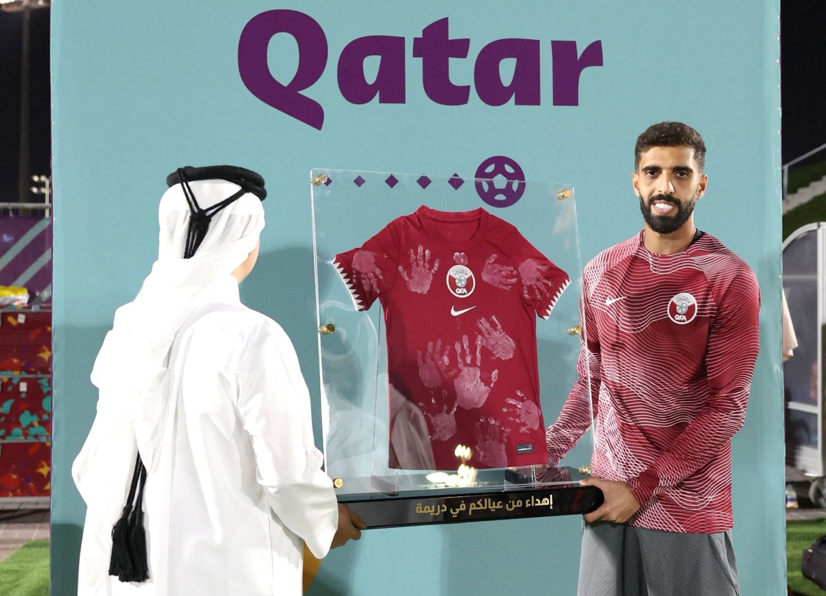 A fan presents a memento to Qatar captain Hassan Al Haydos.