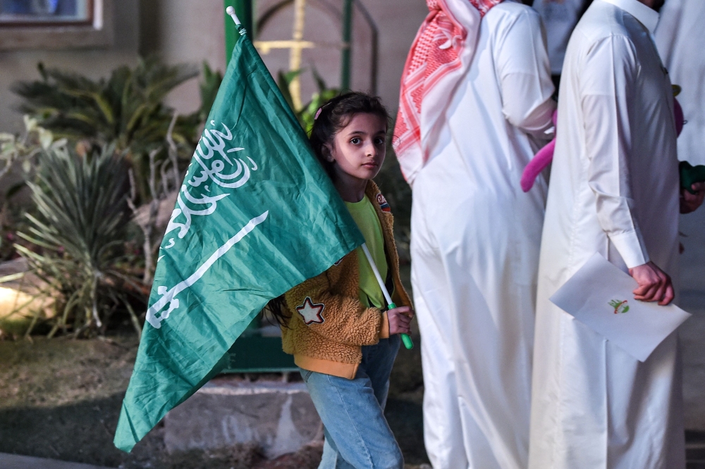 A young Saudi football fan walks with her country's flag during celebrations of Saudi Arabia's win over Argentina in the Qatar 2022 World Cup in the capital Riyadh on November 22, 2022. (Photo by AFP)