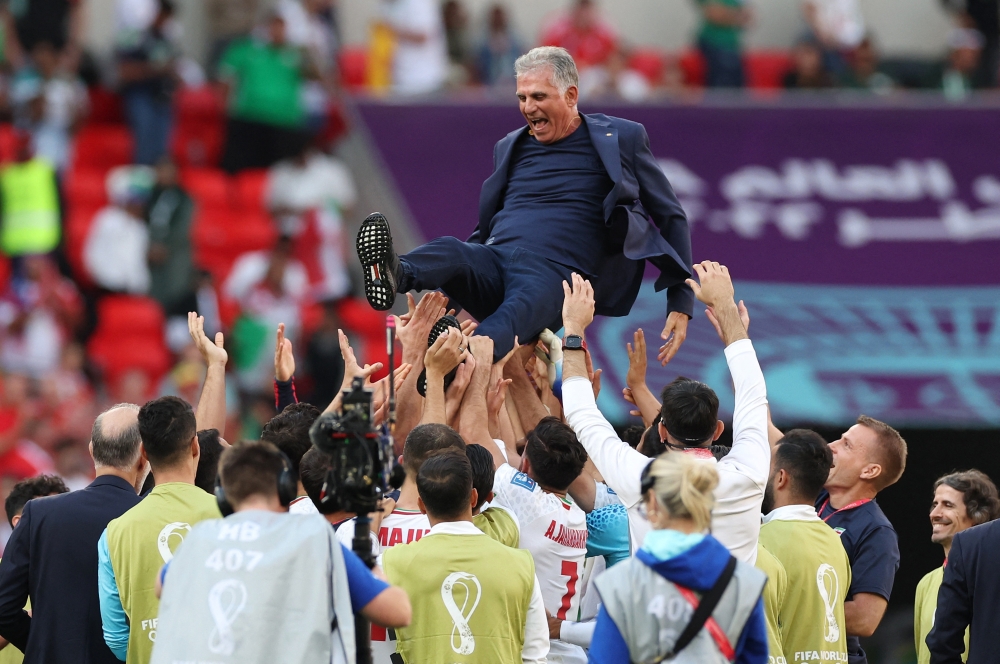 Iran players celebrate with Iran coach Carlos Queiroz after the match against Wales at Ahmad Bin Ali Stadium, Al Rayyan, Qatar, November 25, 2022. (REUTERS/Amanda Perobelli)