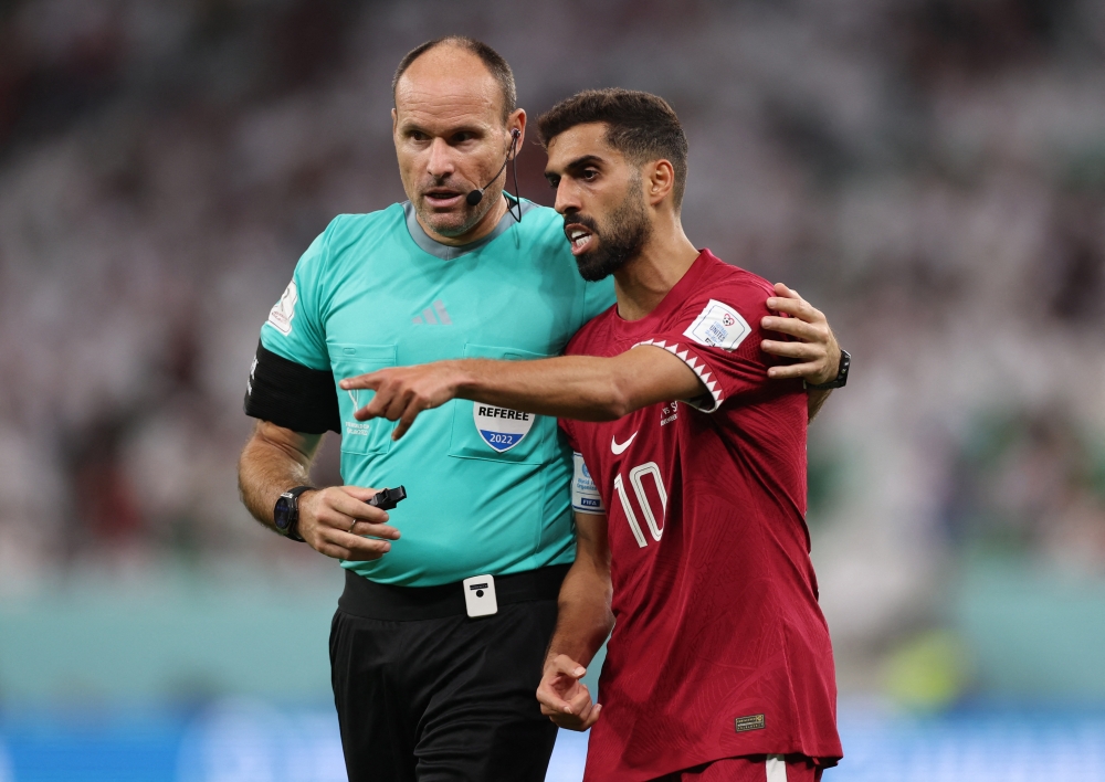 Qatar's Hassan Al-Haydos with referee Antonio Mateu Lahoz during World Cup Qatar 2022 match between Qatar and Senegal at Al Thumama Stadium on November 25, 2022. (REUTERS/Matthew Childs)