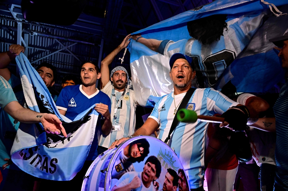 Fans of Argentina's Diego Maradona cheer as the pay tribute on the second anniversary of Maradona's death at a fan zone devoted to the Argentine at Doha's international airport on November 25, 2022. Photo by Javier Soriano / AFP