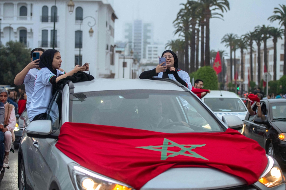 Moroccan football fans celebrate in Rabat after their country's win of the Qatar 2022 World Cup Group F football match between Belgium and Morocco, on November 27, 2022. (Photo by JALAL MORCHIDI / AFP)