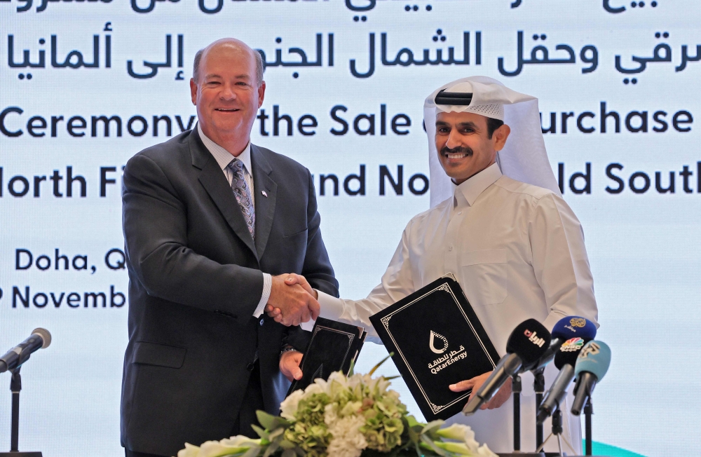 HE Saad Sherida al-Kaabi, Qatar's energy minister and CEO of QatarEnergy, and Ryan Lance, CEO of multinational corporation ConocoPhillips, exchange documents during a press conference in Qatar's capital Doha on November 29, 2022. (Photo by KARIM JAAFAR / AFP)