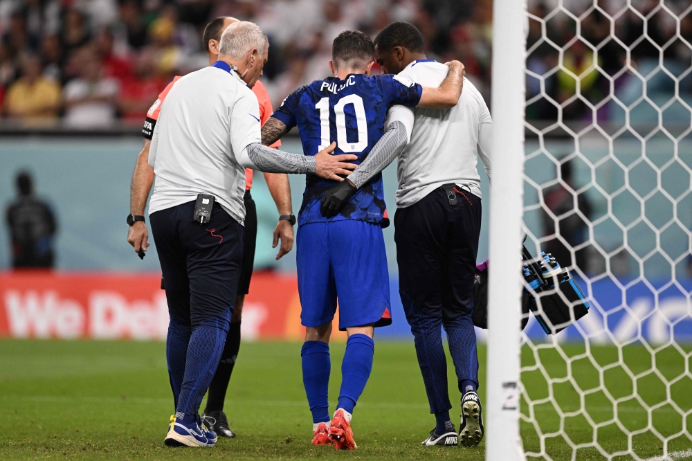 USA's Christian Pulisic receives medical attention after injuring himself while scoring his team's first goal during the Group B match against Iran at the Al-Thumama Stadium in Doha on November 29, 2022. (Photo by Fabrice COFFRINI / AFP)