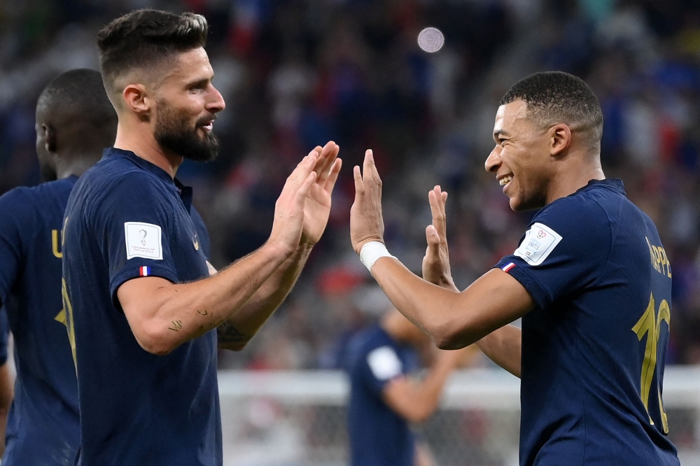 France's forward Kylian Mbappe (right) celebrates scoring his team's second goal with Olivier Giroud during the Qatar 2022 World Cup round of 16 football match between France and Poland at the Al-Thumama Stadium in Doha on December 4, 2022. (Photo by FRANCK FIFE / AFP)