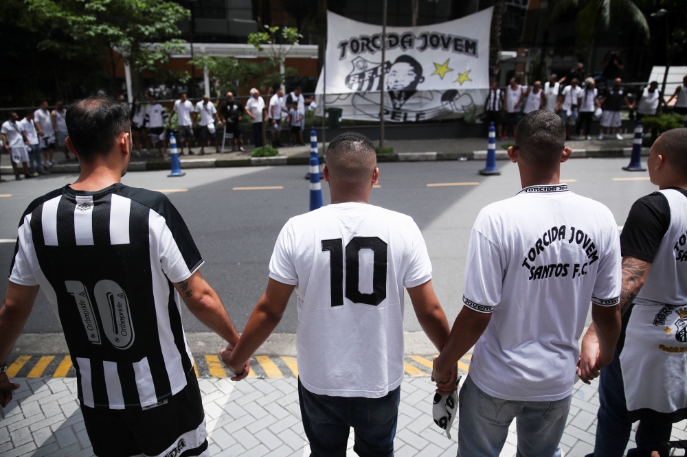 Fans hold hands during a vigil in front of the Albert Einstein Hospital where Brazilian football legend Pele is hospitalized in Sao Paulo, Brazil, December 4, 2022. (REUTERS/Carla Carniel)